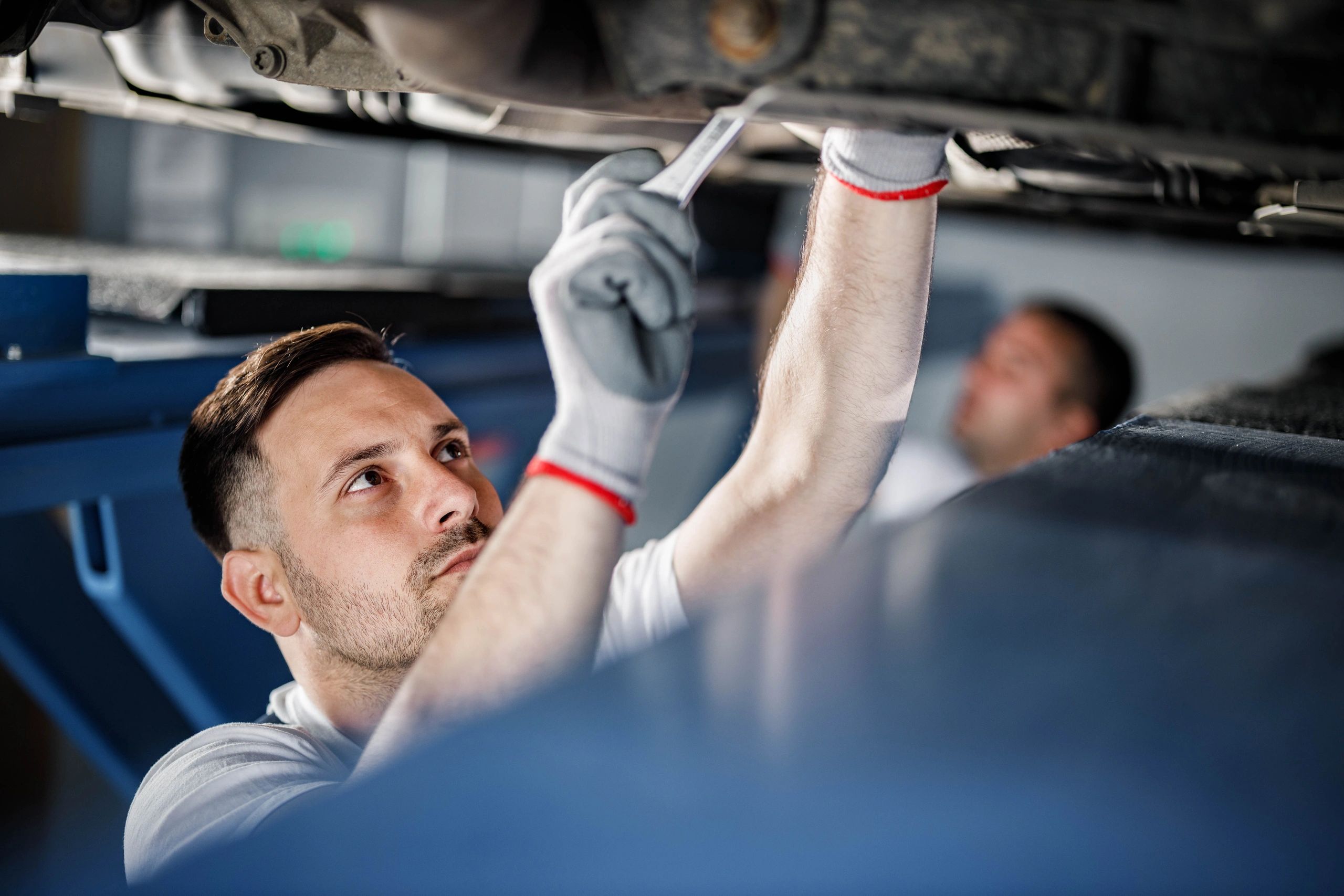 Auto mechanic working under a vehicle on a lift