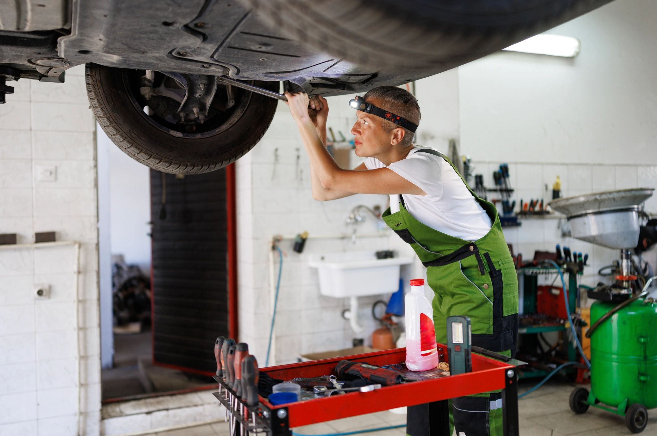 Mechanic working under a vehicle on a lift in a garage