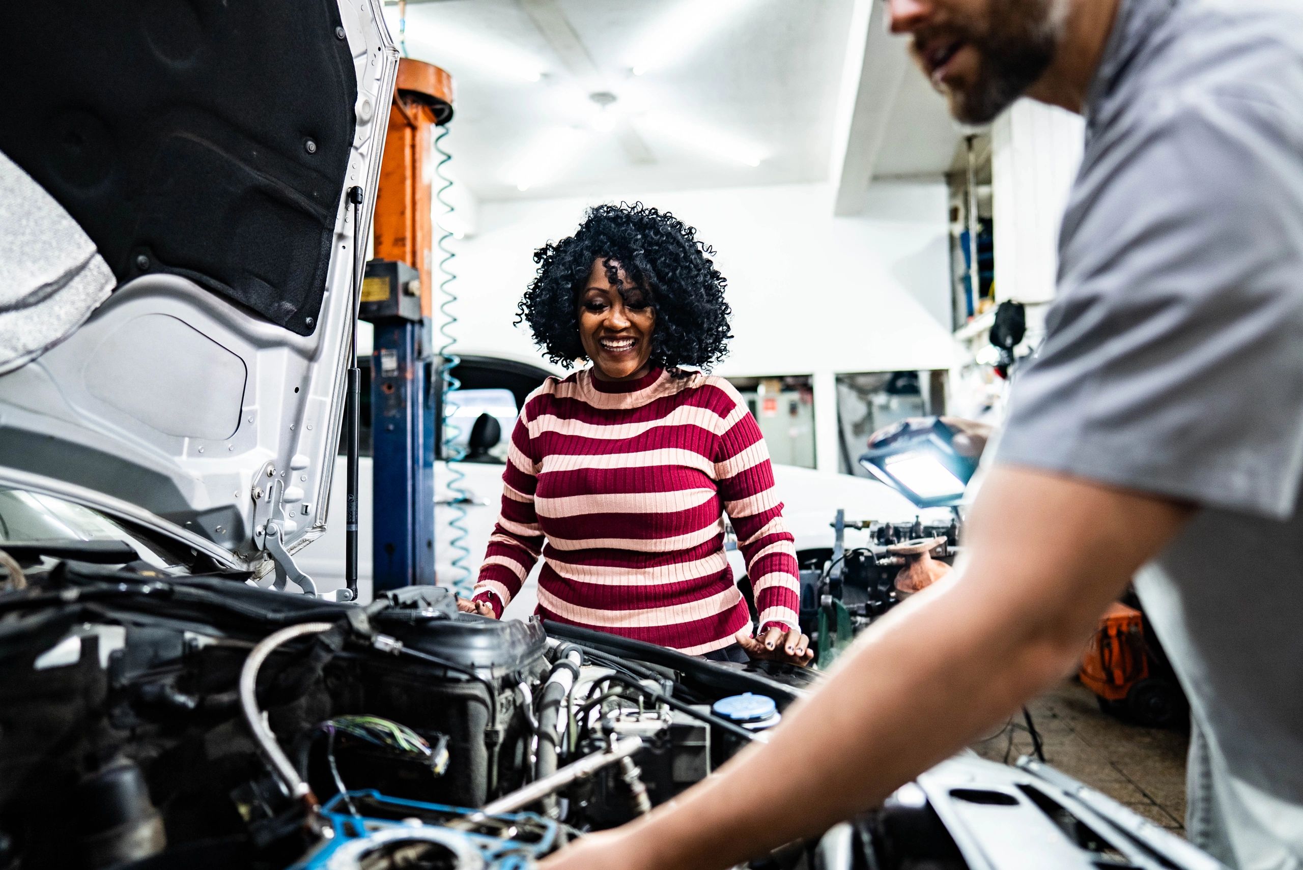 Customer speaking with an auto mechanic at a repair shop counter